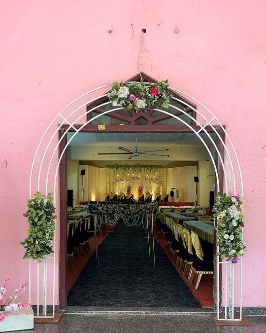 Floral arch entrance opening into a decorated wedding hall