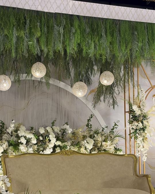 Stage of hanging greenery, white florals and a cream sofa