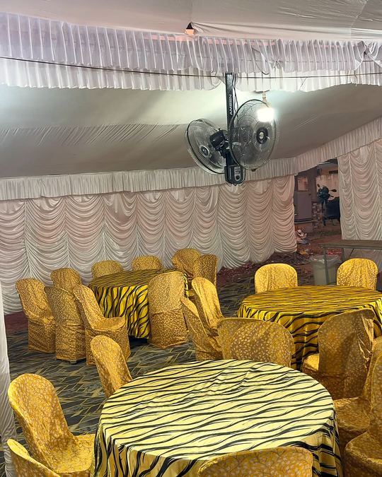 Dining tables with gold chair covers in a draped tent