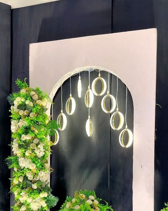 Arched backdrop with suspended glass rings and white roses and greenery