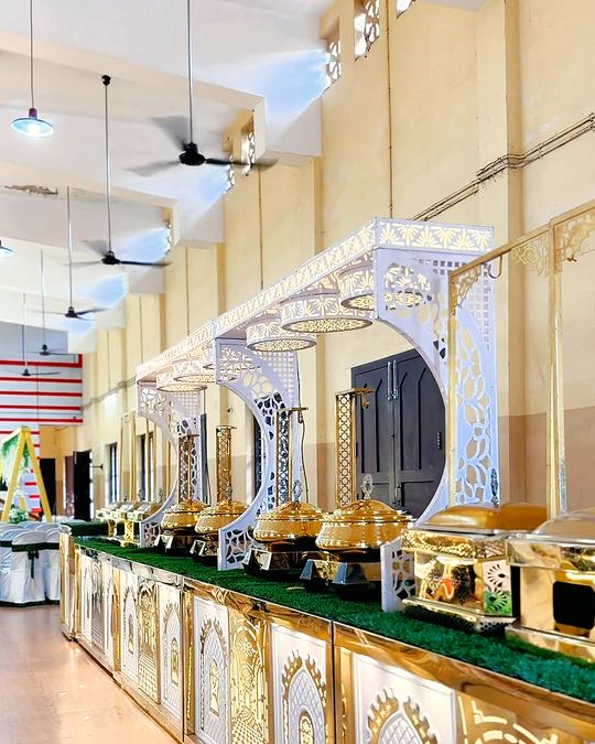 White carved buffet counters with gold chafing dishes along a banquet hall